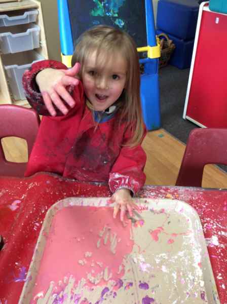 girl painting showing her messy hand